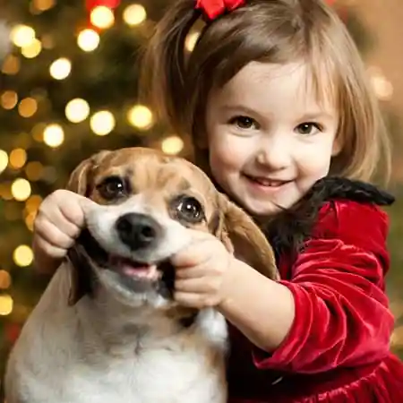 Criança sorrindo enquanto segura o rosto de um cachorro ilustrando contraste entre sorriso espontâneo humano e sorriso induzido