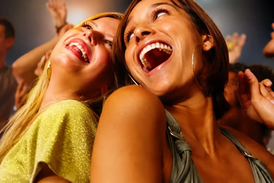 Duas mulheres sorrindo amplamente em contexto social, imagem usada para análise de congruência emocional e identificação de sorriso falso.