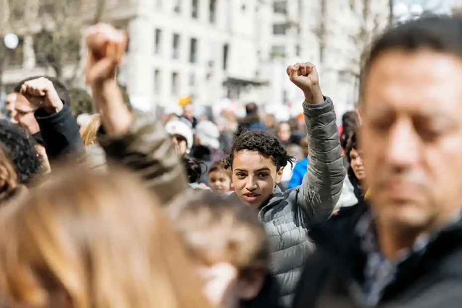 Jovem em manifestação pública com punho levantado, representando engajamento cívico infantojuvenil e participação democrática.